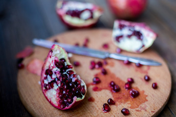 organic pomegranate open cut in half and full one on a wooden dark table background decorated in rustic style