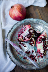 organic pomegranate open cut in half and full one on a wooden dark table background decorated in rustic style