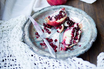 organic pomegranate open cut in half and full one on a wooden dark table background decorated in rustic style