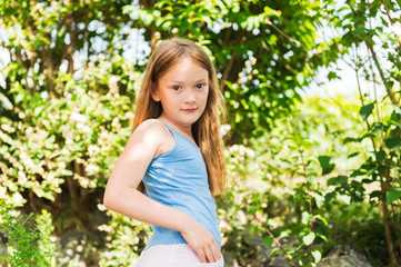 Outdoor portrait of a cute little girl playing in a garden on a nice sunny day