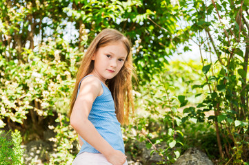 Outdoor portrait of a cute little girl playing in a garden on a nice sunny day