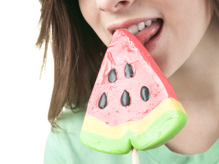 Charming young woman licks tasty sugar candy, it is isolated on white background.