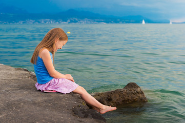 Cute little girl playing by the lake in the evening