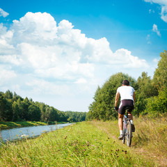 Cyclist Riding a Bike on River Bank