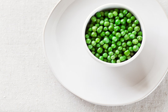 Cooked Peas from above in a white bowl with copy space. 