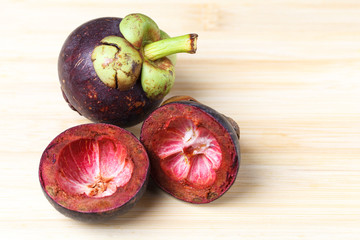 Mangosteen and cross section showing the thick purple skin