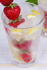 Lemonade with fresh strawberries mint and lemon on wooden background