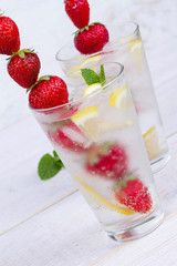 Lemonade with fresh strawberries mint and lemon on wooden background