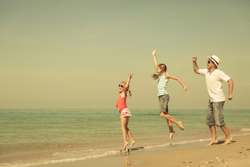 Father and daughters playing on the beach at the day time.