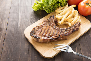 Grilled steak with french fries on a wooden board.