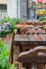 Fototapeta na wymiar Medieval style outdoor terrace. Empty wooden tables on rainy day