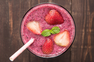 Strawberry smoothie in glass on wooden background