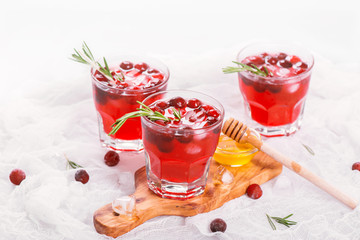 Cranberry cocktail with rosemary garnish, honey and soda on wooden background. Selective focus