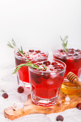 Cranberry cocktail with rosemary garnish, honey and soda on wooden background. Selective focus