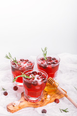 Cranberry cocktail with rosemary garnish, honey and soda on wooden background. Selective focus