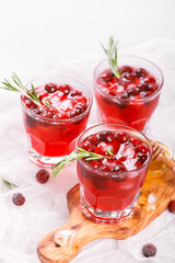 Cranberry cocktail with rosemary garnish, honey and soda on wooden background. Selective focus