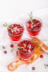 Cranberry cocktail with rosemary garnish, honey and soda on wooden background. Selective focus