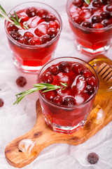 Cranberry cocktail with rosemary garnish, honey and soda on wooden background. Selective focus
