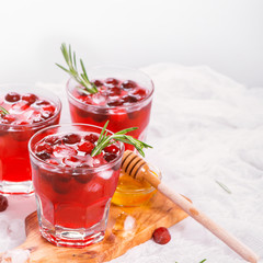 Cranberry cocktail with rosemary garnish, honey and soda on wooden background. Selective focus
