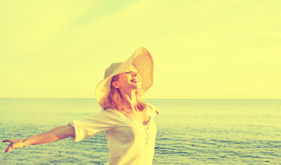 Happy beauty woman in hat opened his hands, enjoys sunset over s