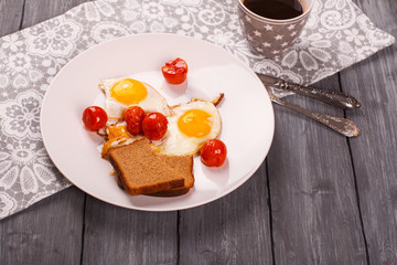 Fried eggs with cherry tomatoes and mug of black coffee. Breakfast concept. Selective focus