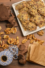 Overhead view of homemade chocolate walnut cookies with ingredients and gift wrap supplies.