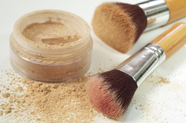 Make up mineral powder in plastic jar with cosmetic brushes on white background