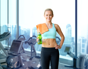happy woman with bottle of water and towel in gym