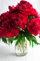 Red peony bouquet in glass vase on table