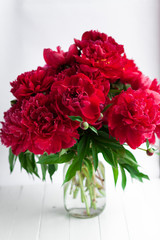 Red peony in glass vase on wood table