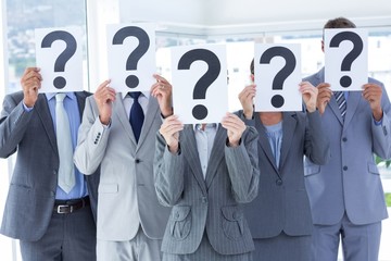 Business colleagues hiding their face with question mark sign