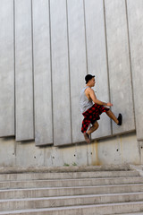 cool young and handsome caucasian brunette hipster skater guy wearing a hat posing smiling and having fun outside during amazing summer day in the city with