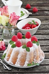 Vanilla bundt cake with raspberries on a rustic dark background 