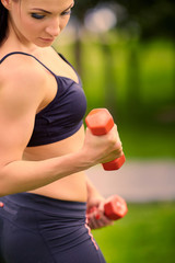 Female fitness instructor exercising with small weights in green