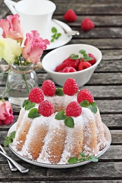 Vanilla bundt cake with raspberries on a rustic dark background 