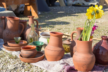 pottery utensils, glass and flowers on ground
