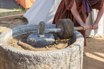 man works at ancient Roman press for olive oil