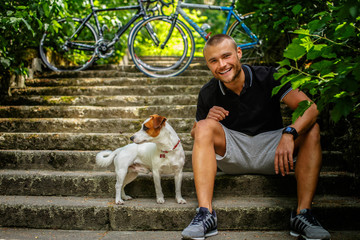 Obraz premium Man with dog sitting on stairs.
