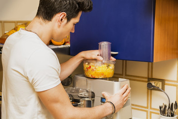 Fototapeta na wymiar Young man preparing healthy fruit smoothie
