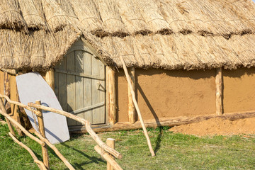 clay house with a thatched roof and shield alongside door