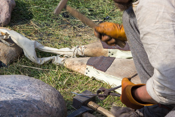 hands of a blacksmith hammering nail using ancient tools