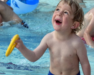 Cute blonde boy plays in swimming pool