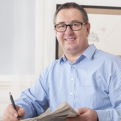 Man with glasses reading newspaper