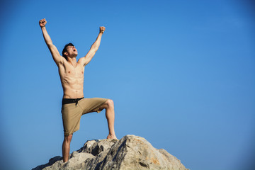 Successful sexy muscular shirtless man with fists raised