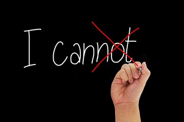 Hand with pen writing I cannot to give positive thinking and motivation isolated on black...