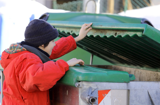 poor young boy tries to eat into the waste box in winter