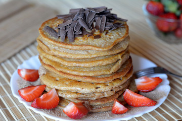 Stack of sweet pancakes with strawberries and cinnamon sugar and chocolate