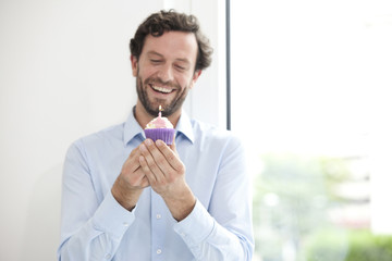 Smiling businessman holding birthday cupcake