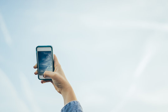 Germany, woman shooting to sky with a smartphone