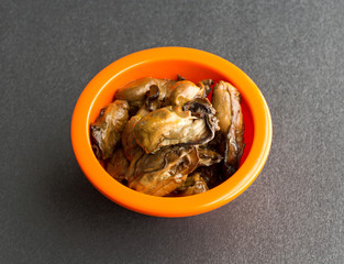 Bowl of smoked oysters on a black table top